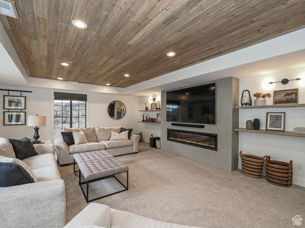Living room featuring wooden ceiling, carpet, recessed lighting, and a glass covered fireplace