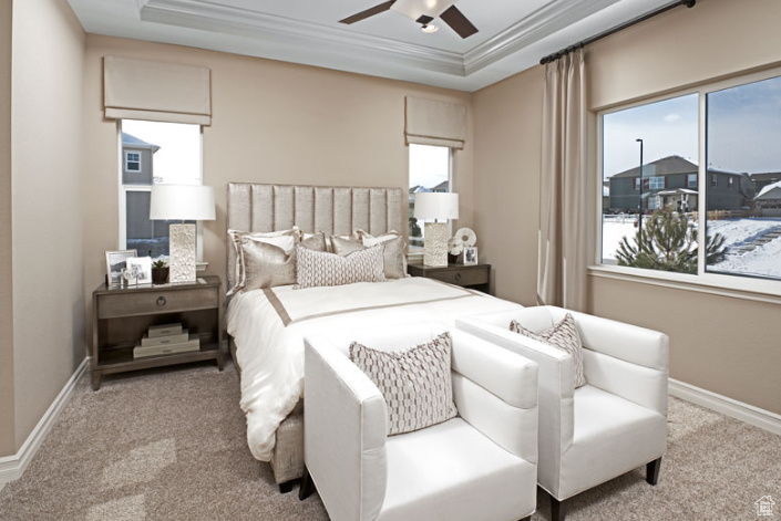 Bedroom with carpet floors, a raised ceiling, crown molding, baseboards, and a ceiling fan