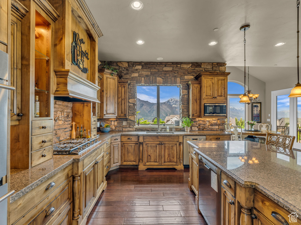 Kitchen with stainless steel appliances, a sink, brown cabinets, dark wood finished floors, and backsplash