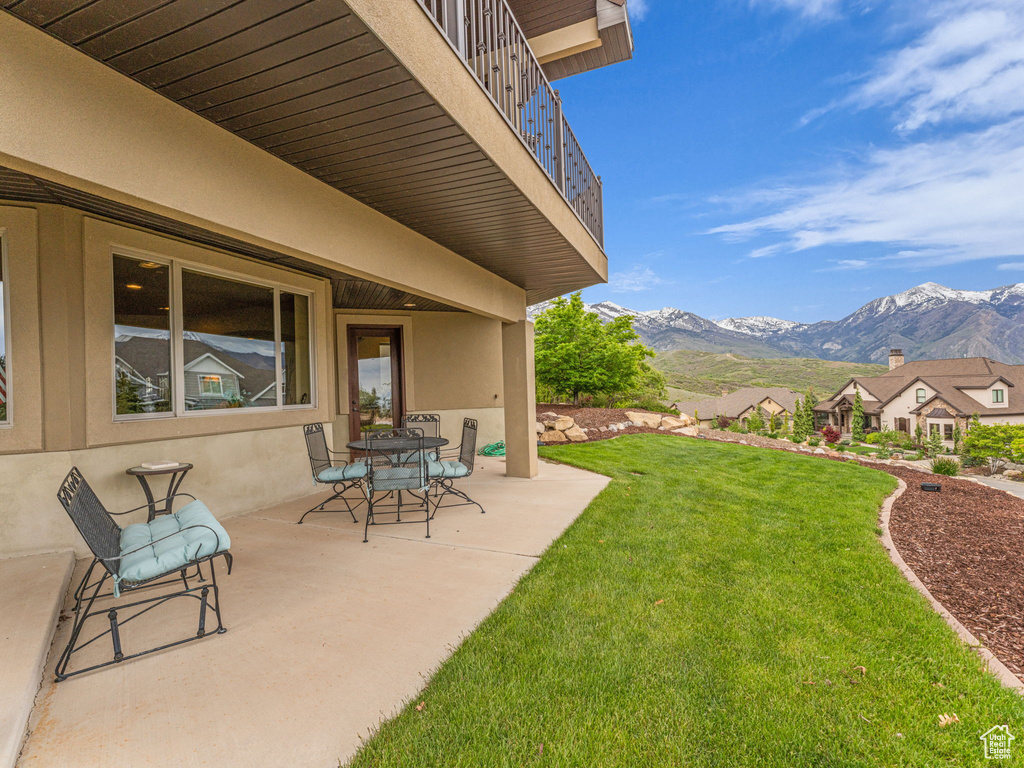 View of green lawn featuring a mountain view, a patio area, and a balcony