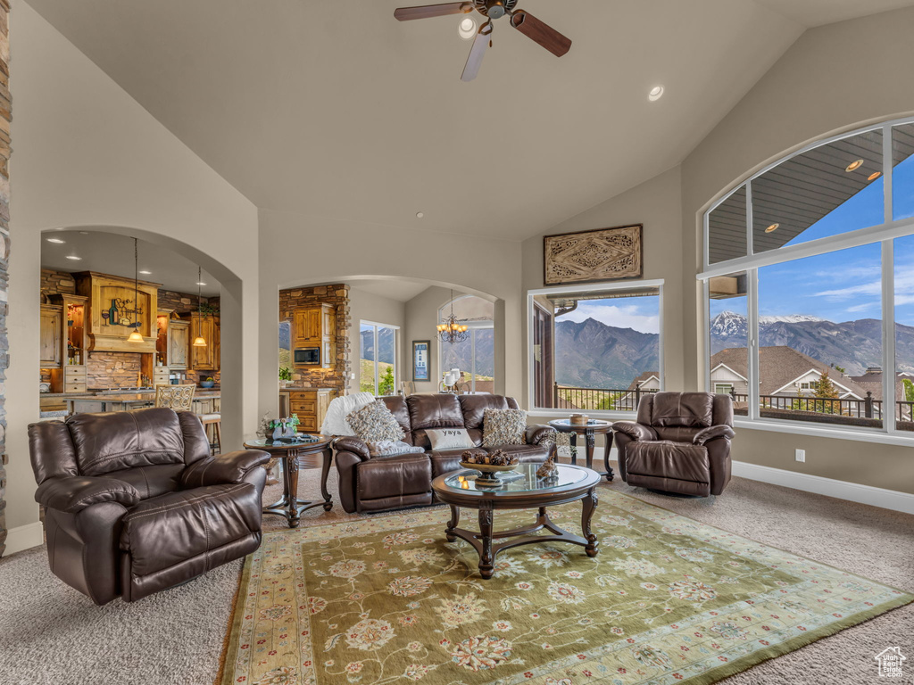 Living room with a chandelier, arched walkways, a mountain view, carpet, and ceiling fan