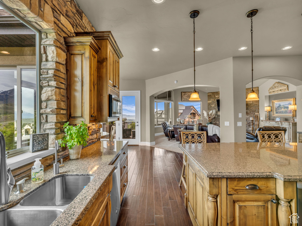 Kitchen featuring arched walkways, a sink, brown cabinets, dark wood-style flooring, and recessed lighting