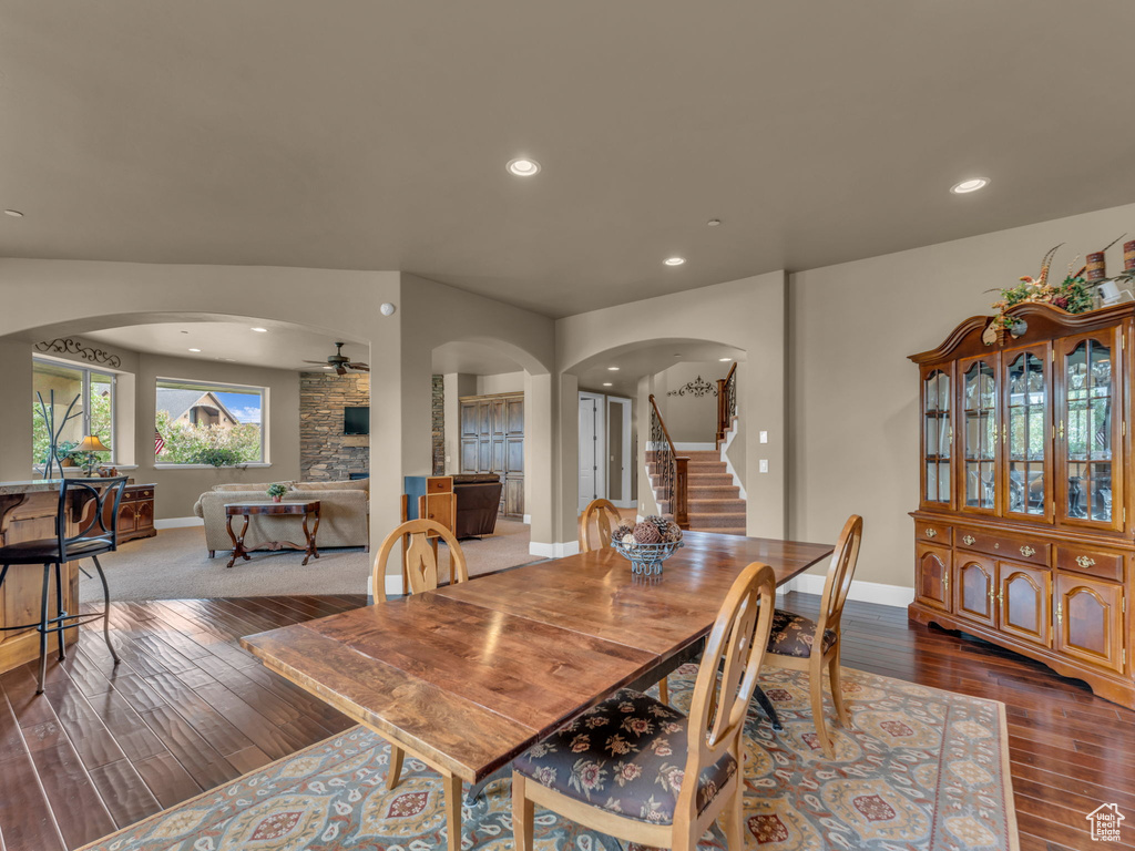 Dining space featuring arched walkways, a ceiling fan, hardwood / wood-style flooring, stairway, and baseboards