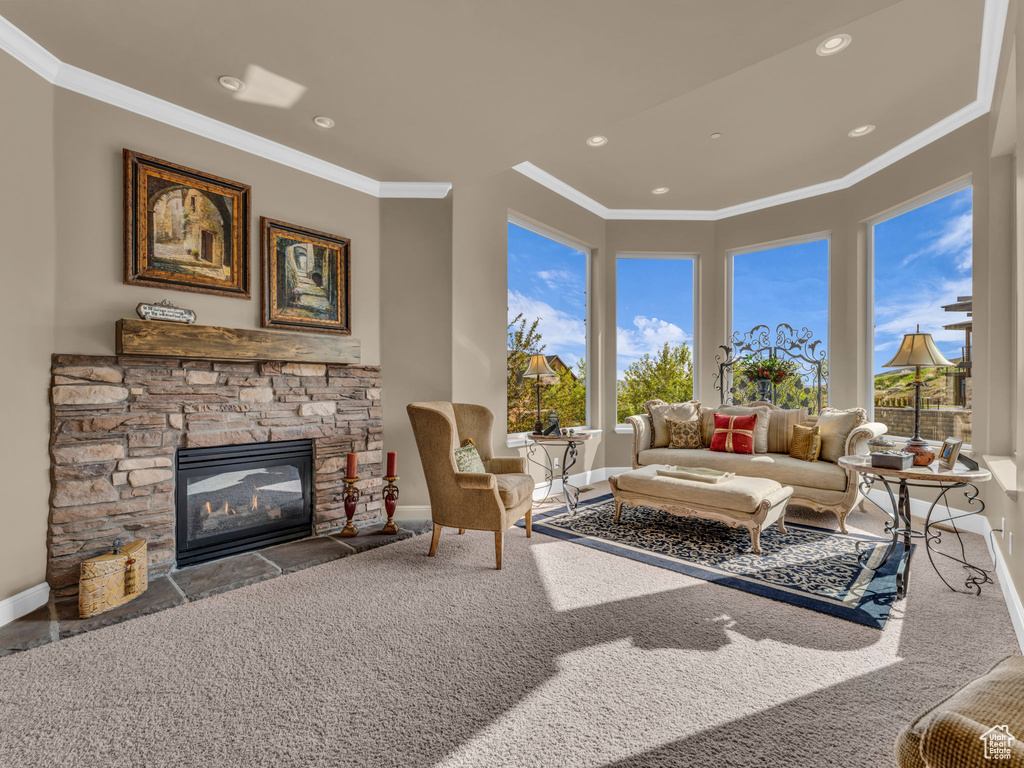 Carpeted living room with baseboards, crown molding, a stone fireplace, and recessed lighting