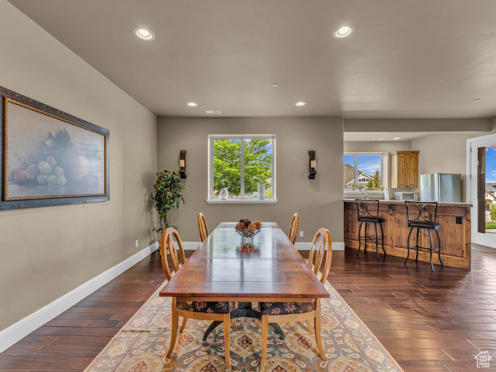 Dining room featuring plenty of natural light, dark wood-style flooring, recessed lighting, and baseboards