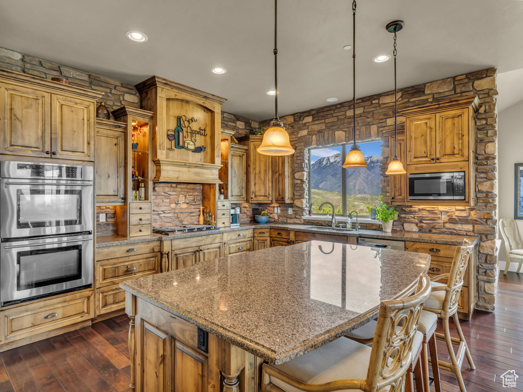 Kitchen featuring appliances with stainless steel finishes, decorative backsplash, recessed lighting, a kitchen island, and stone countertops