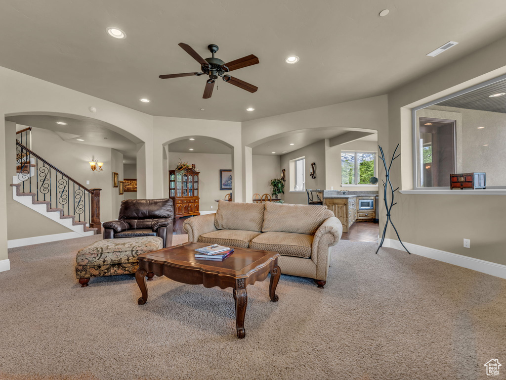 Carpeted living area featuring baseboards, recessed lighting, a ceiling fan, stairs, and arched walkways