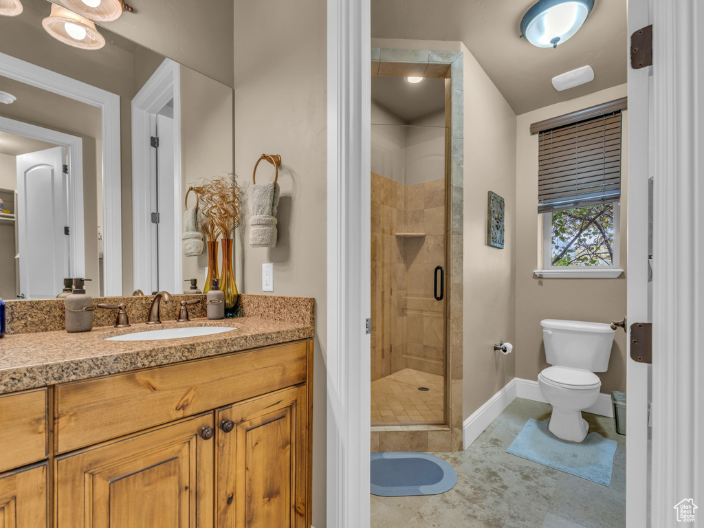 Bathroom featuring a shower stall, baseboards, toilet, and vanity