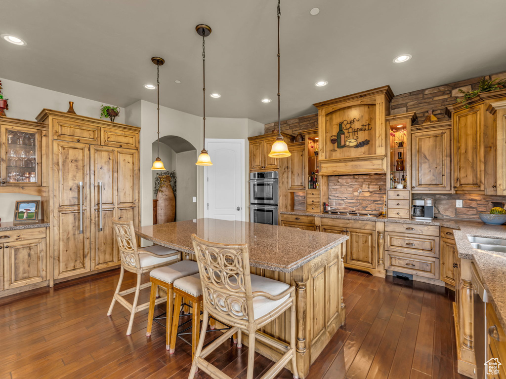 Kitchen featuring stainless steel appliances, arched walkways, backsplash, dark wood-style flooring, and recessed lighting