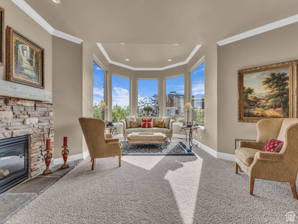 Living room featuring crown molding, baseboards, a stone fireplace, carpet, and recessed lighting