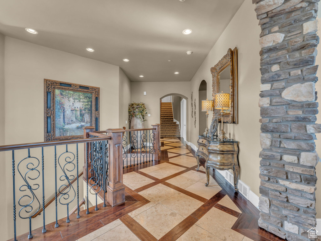 Foyer entrance with arched walkways, inlaid floor details, recessed lighting, and baseboards