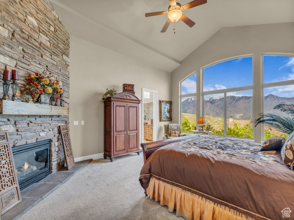 Bedroom with a mountain view, light carpet, a fireplace, high vaulted ceiling, and baseboards