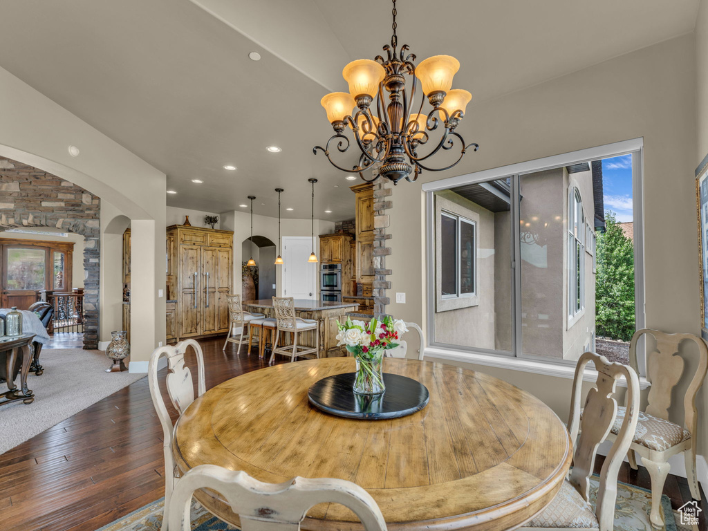 Dining room with arched walkways, dark wood-style flooring, plenty of natural light, a chandelier, and recessed lighting