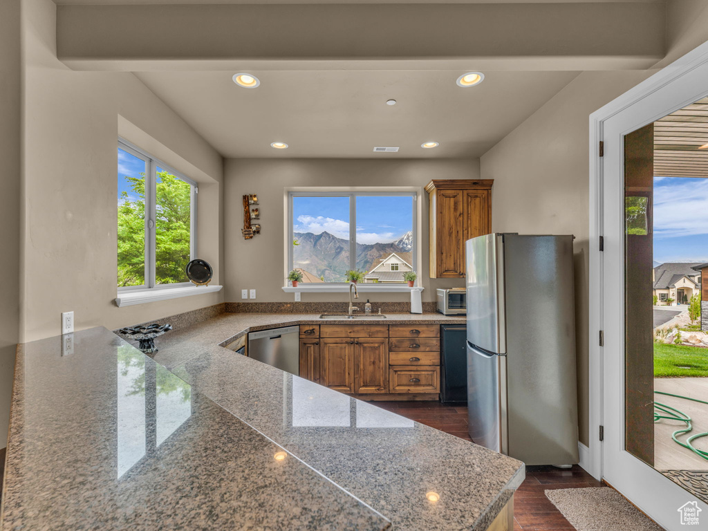 Kitchen featuring appliances with stainless steel finishes, brown cabinets, a sink, dark wood-type flooring, and recessed lighting