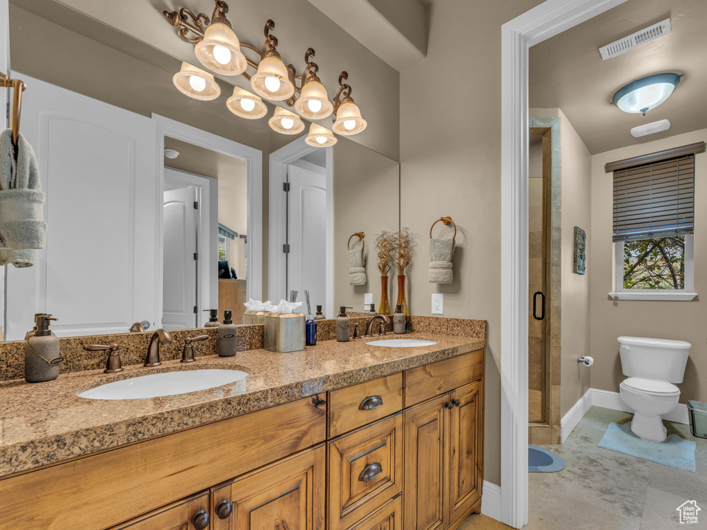 Bathroom with toilet, baseboards, a shower stall, and double vanity