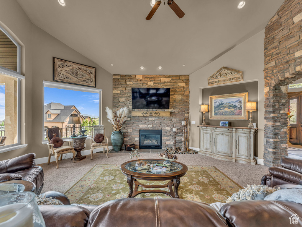 Carpeted living room with a stone fireplace, a ceiling fan, high vaulted ceiling, recessed lighting, and baseboards