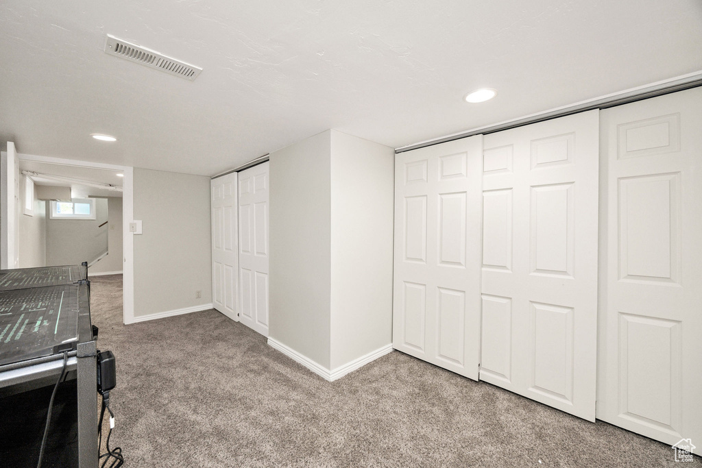 Unfurnished living room featuring carpet flooring, baseboards, and recessed lighting