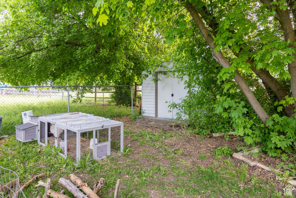 View of yard with fence, an outdoor structure, and a shed
