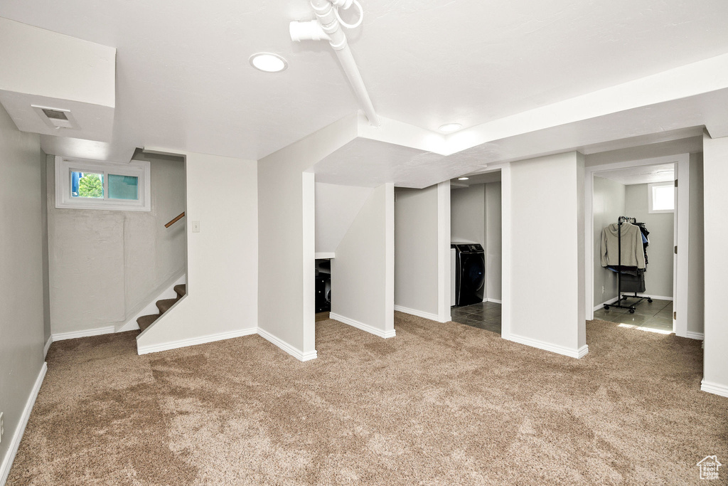 Below grade area with carpet flooring, stairs, baseboards, and washer / clothes dryer