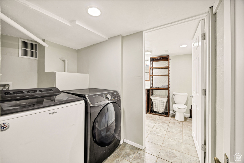 Laundry room featuring separate washer and dryer, baseboards, and light tile patterned floors