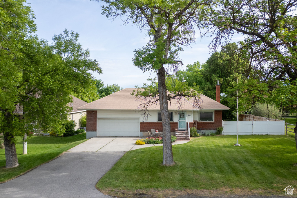 Ranch-style home featuring brick siding, an attached garage, driveway, and a chimney