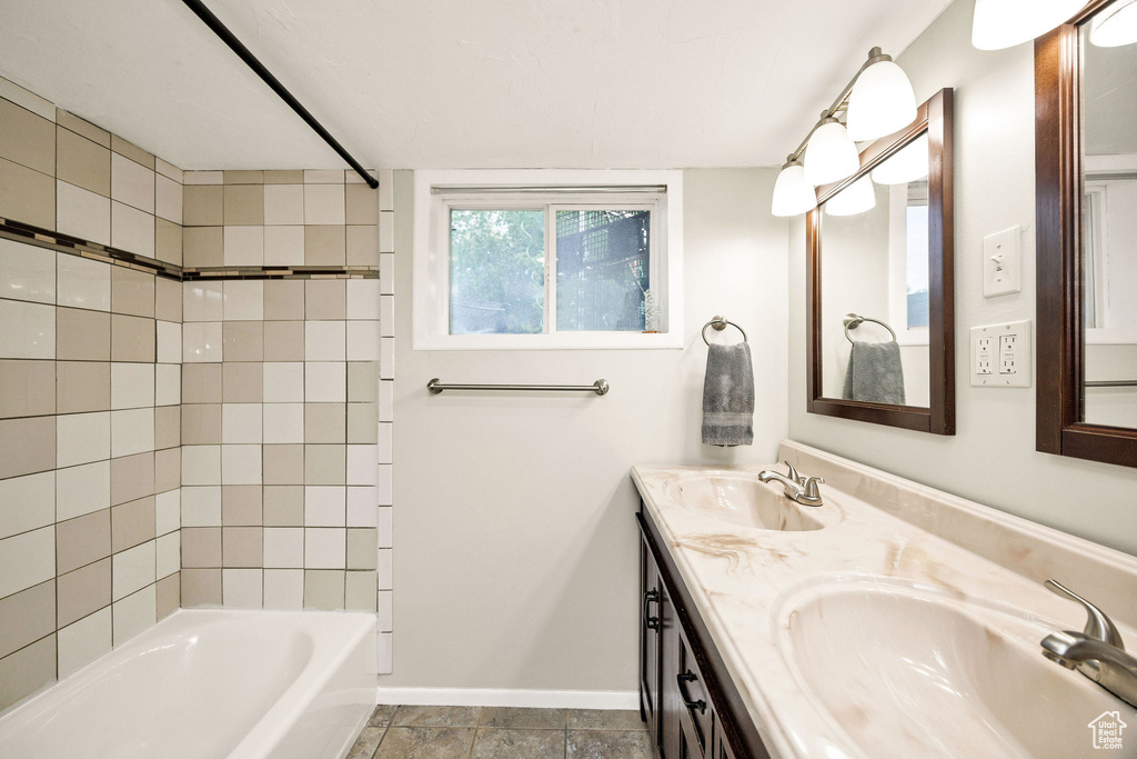 Full bathroom with bathing tub / shower combination, baseboards, and double vanity