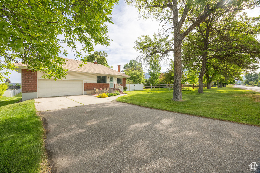 Ranch-style house with brick siding, a chimney, driveway, and an attached garage