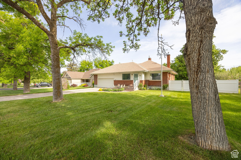 View of front facade featuring brick siding, driveway, a garage, and a chimney