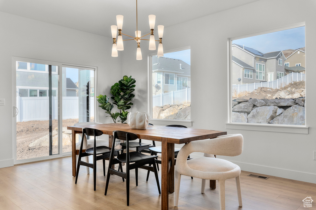 Dining room with light wood-style flooring, healthy amount of natural light, baseboards, and a chandelier