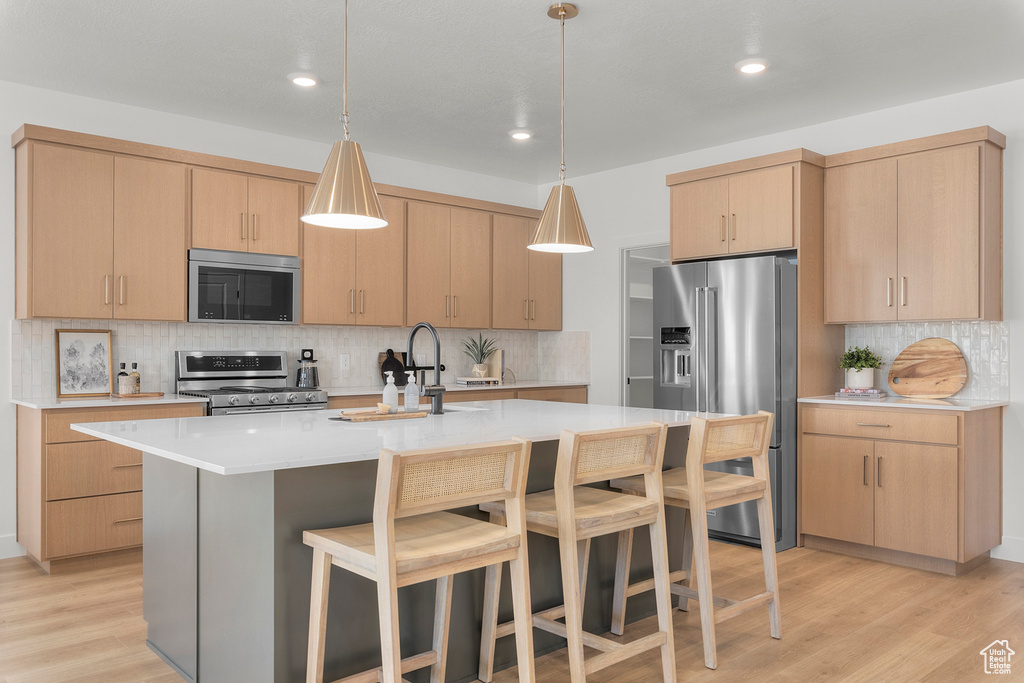 Kitchen featuring appliances with stainless steel finishes, light brown cabinets, decorative backsplash, light countertops, and recessed lighting