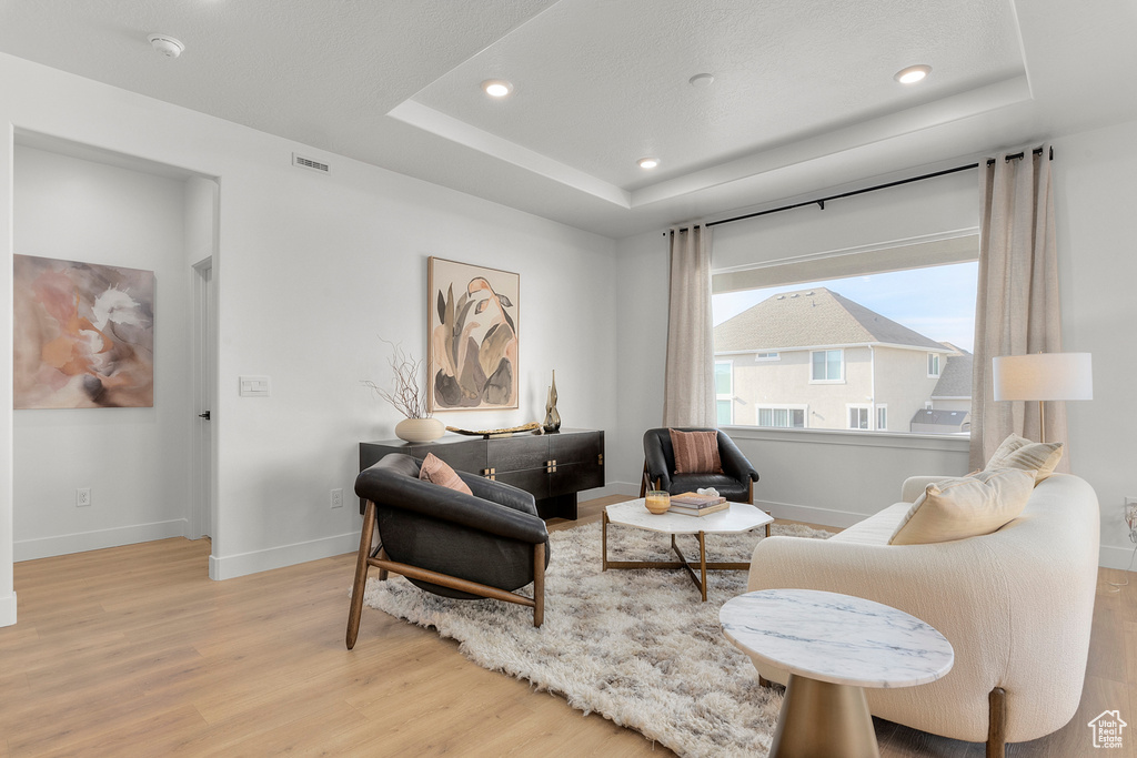Sitting room featuring wood finished floors, a tray ceiling, baseboards, and recessed lighting