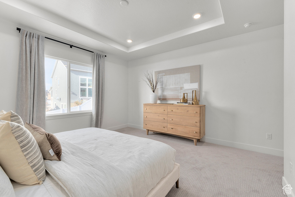 Bedroom featuring light colored carpet, baseboards, recessed lighting, and a tray ceiling