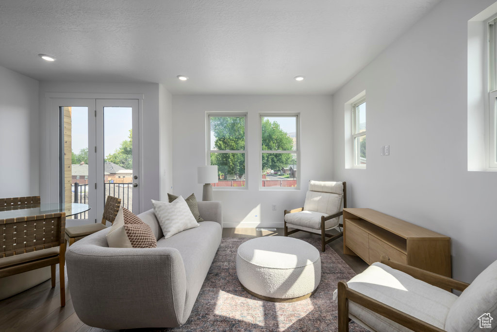 Living room with plenty of natural light, wood finished floors, and recessed lighting