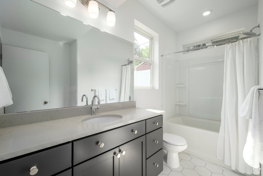 Bathroom with toilet, vanity, tile patterned flooring, and shower / bathtub combination with curtain
