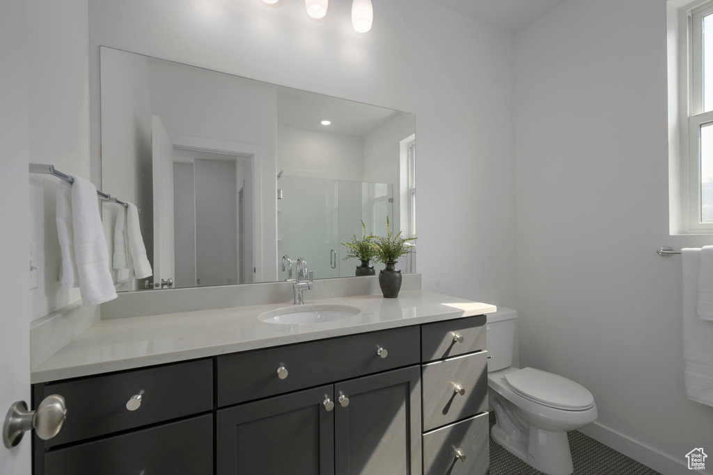 Bathroom with toilet, vanity, baseboards, and tile patterned floors