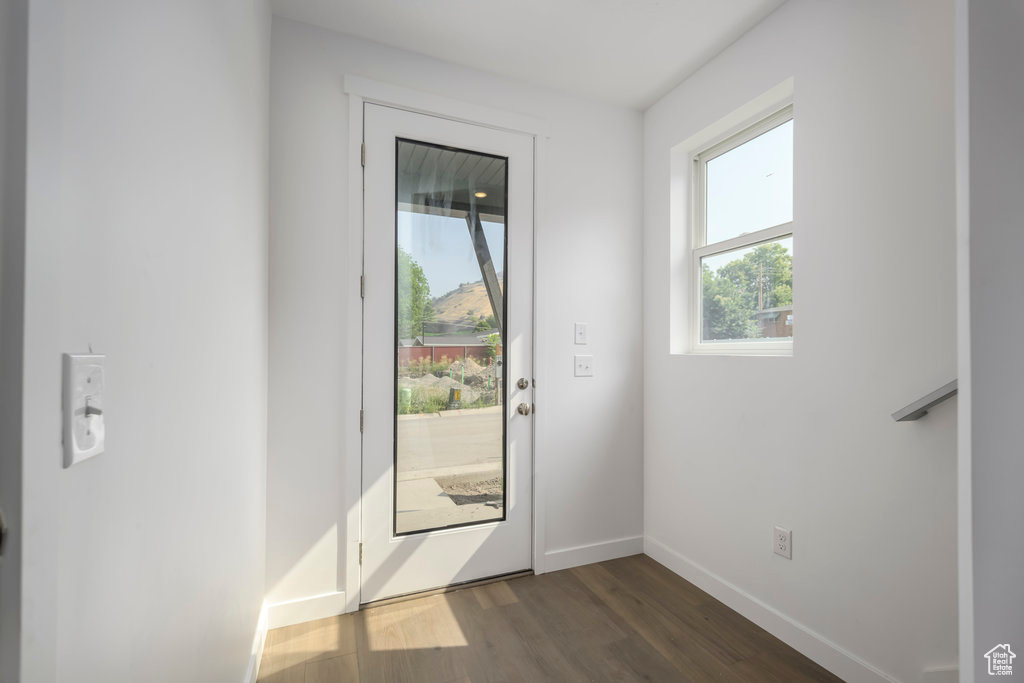 Doorway with dark wood-type flooring and baseboards