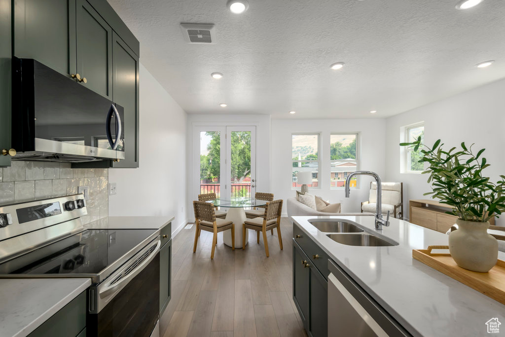 Kitchen featuring appliances with stainless steel finishes, a sink, light countertops, recessed lighting, and wood finished floors
