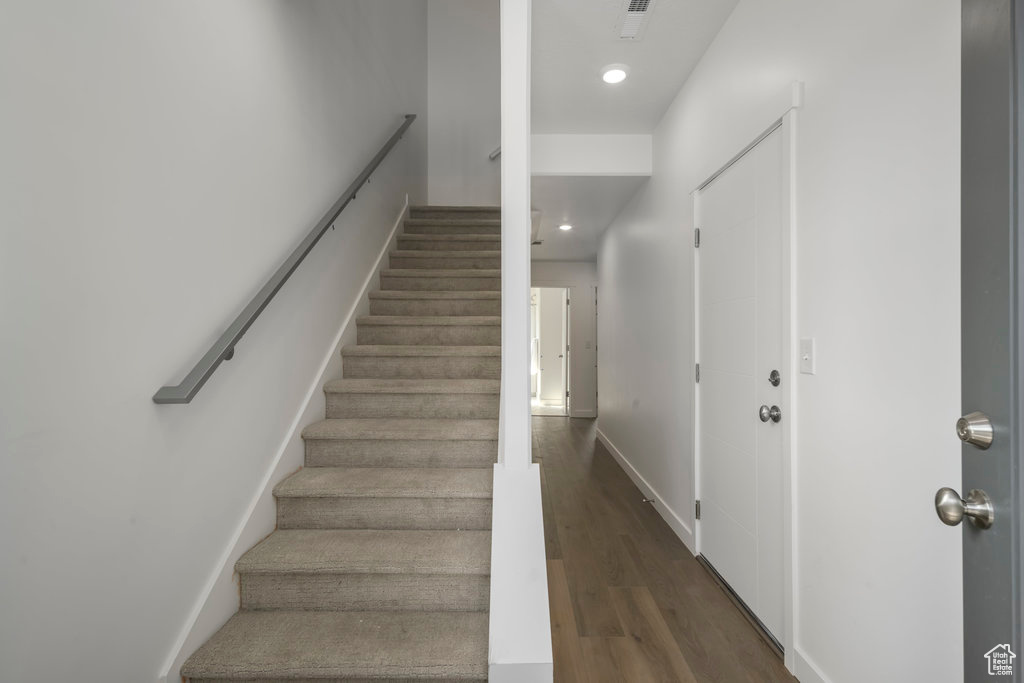 Stairs with wood finished floors, recessed lighting, and baseboards