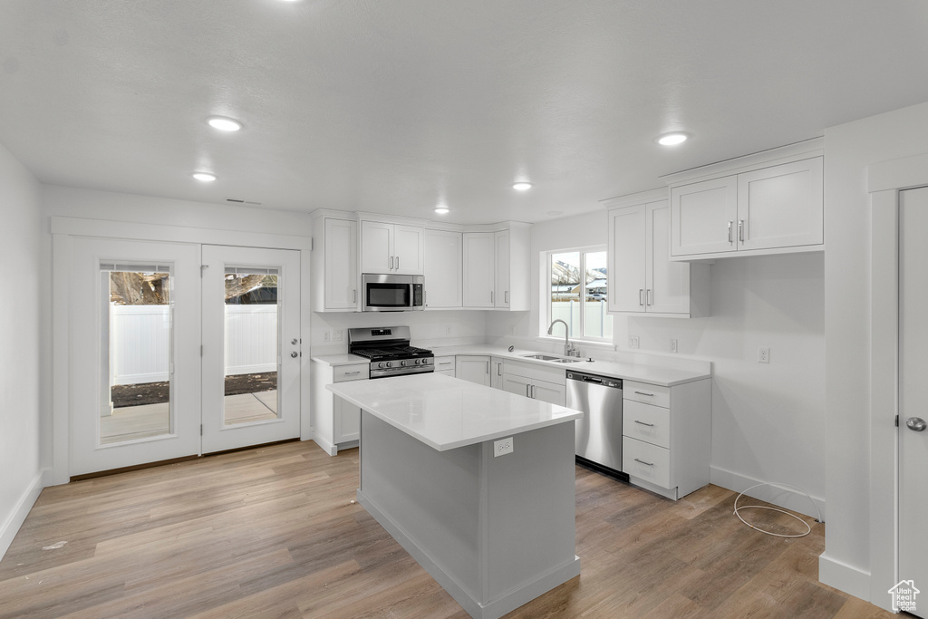 Kitchen featuring stainless steel appliances, a sink, white cabinetry, a center island, and recessed lighting