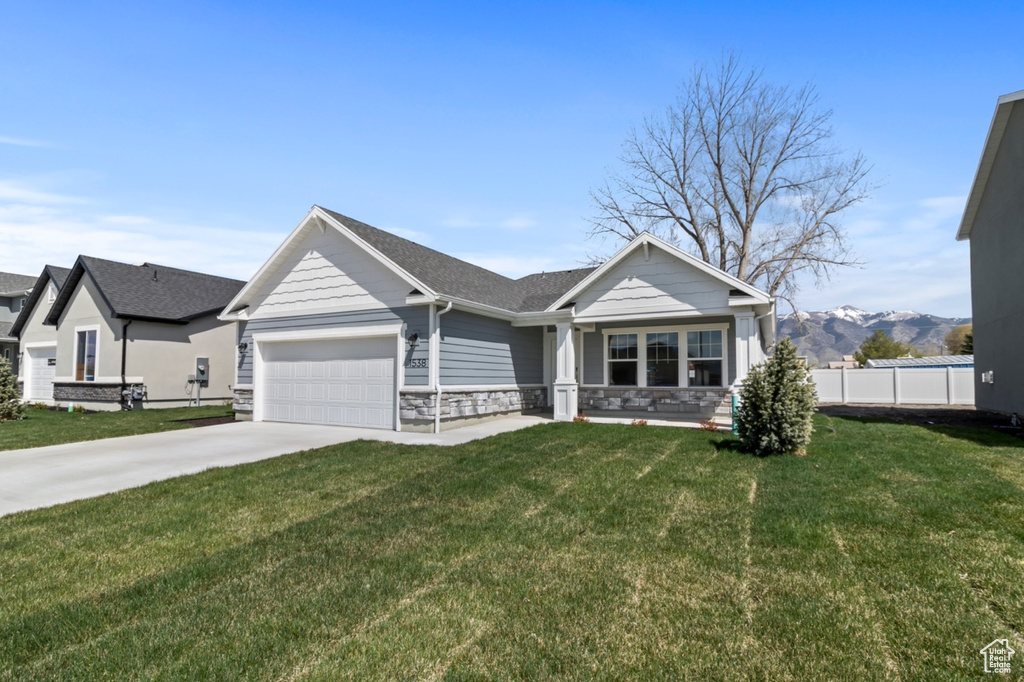 View of front facade featuring a garage, concrete driveway, stone siding, a shingled roof, and a mountain view