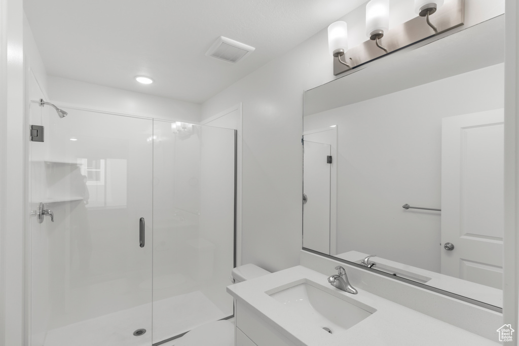 Bathroom with a shower stall, vanity, toilet, and recessed lighting