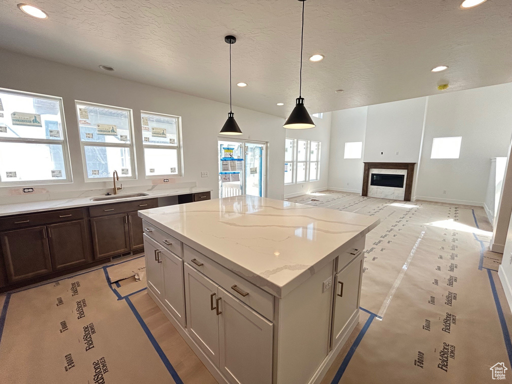 Kitchen featuring recessed lighting, a center island, a textured ceiling, decorative light fixtures, and a glass covered fireplace
