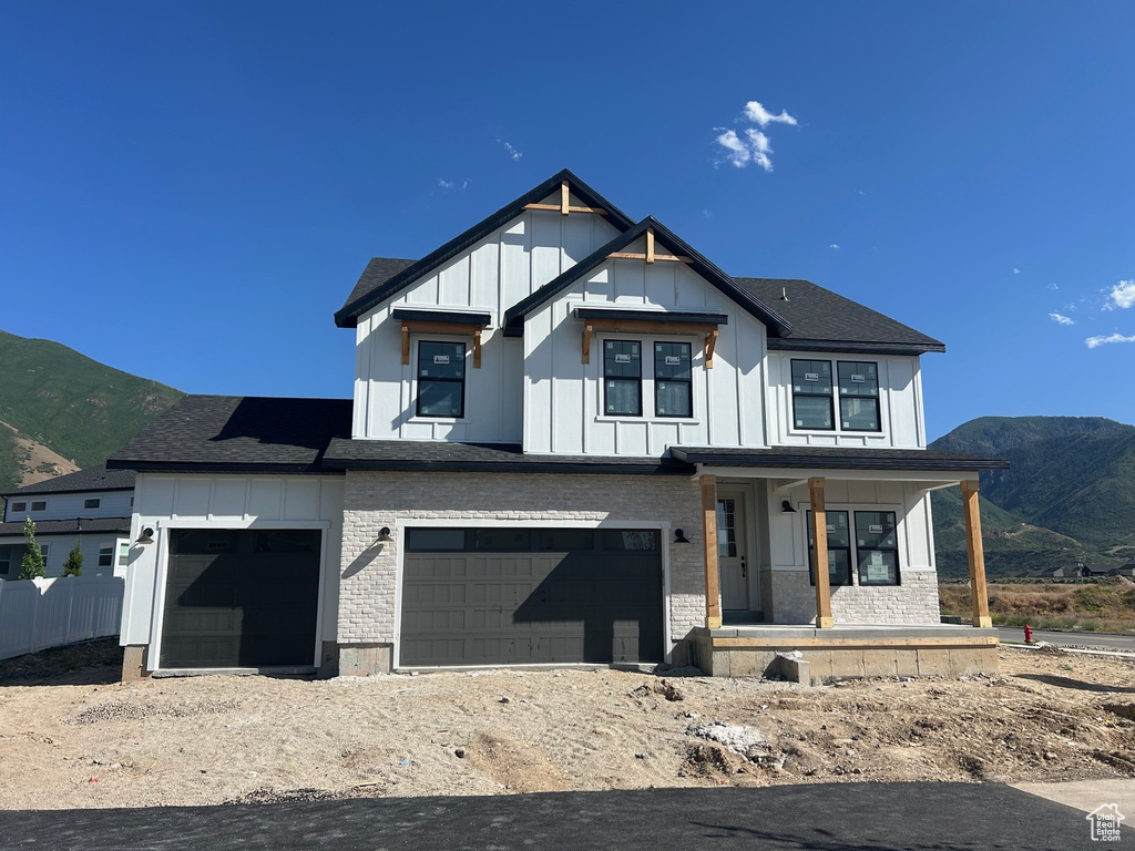 Modern farmhouse style home with board and batten siding, a porch, and a mountain view