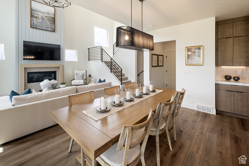 Dining area with dark wood finished floors, stairway, a large fireplace, and baseboards