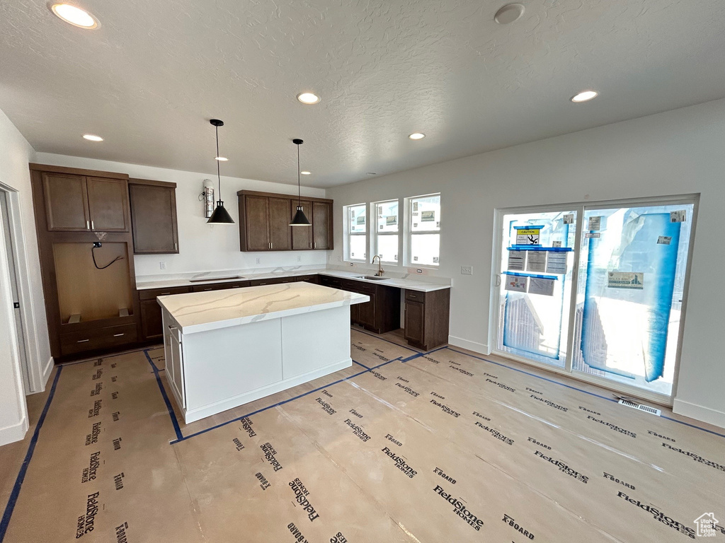 Kitchen featuring recessed lighting, a center island, dark brown cabinets, stovetop, and hanging light fixtures
