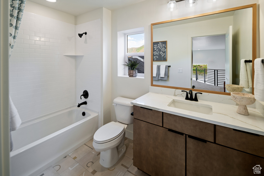 Bathroom with healthy amount of natural light, toilet, shower / bath combination with curtain, and vanity