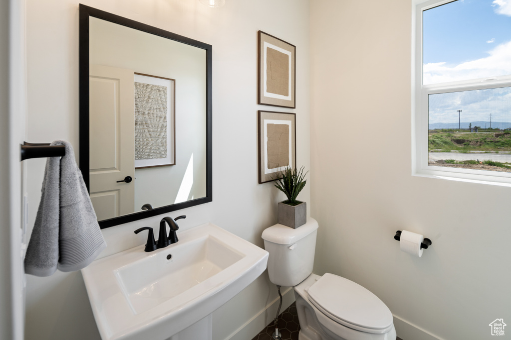 Half bath with toilet, a sink, and baseboards