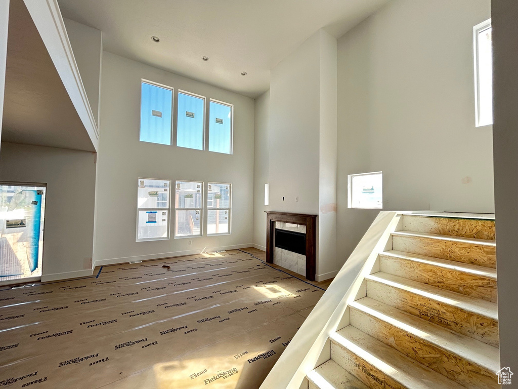 Unfurnished living room featuring a high ceiling, stairway, and a fireplace