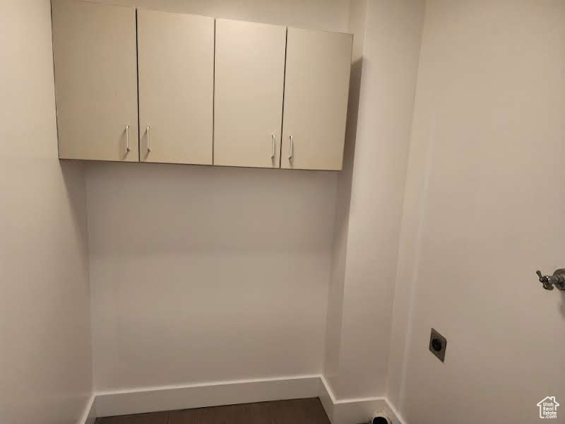 Laundry room with electric dryer hookup, cabinet space, and baseboards