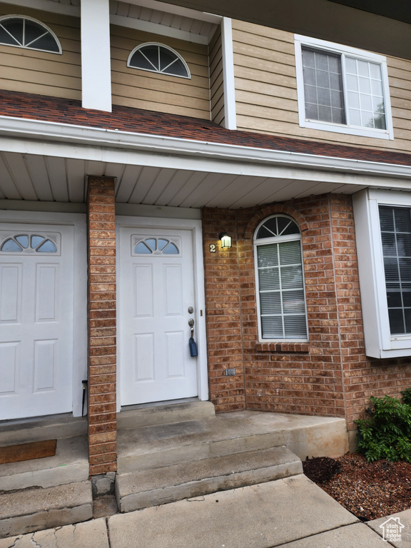 Doorway to property with covered porch and brick siding